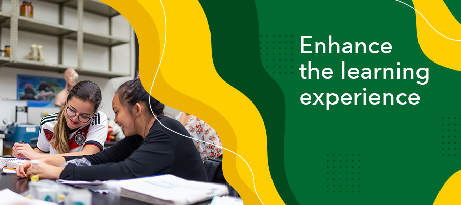 Enhance the learning experience Photo of two female students smiling while working with each other